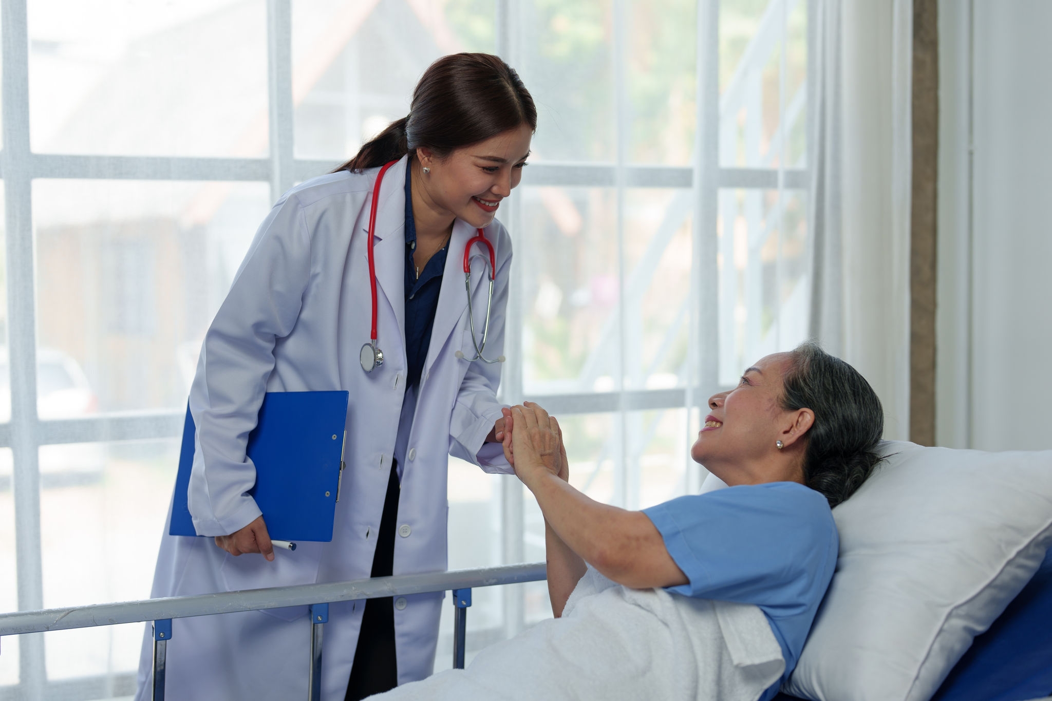 A friendly doctor talks with a retired female patient resting in bed. Full recovery after illness Doctor gives advice on health care Physical examination, treatment advice, medicine, health insurance