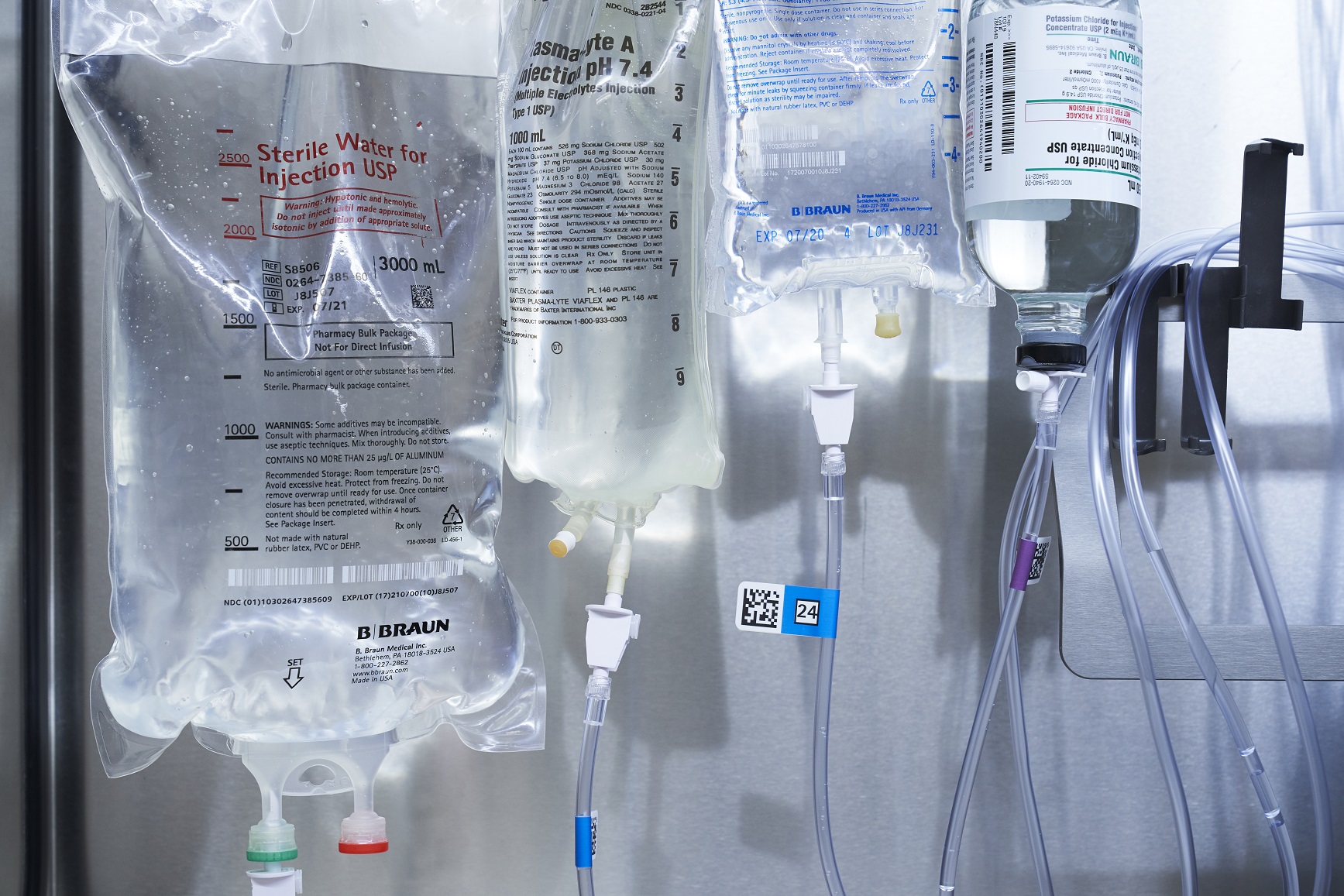 IV bags hanging in a healthcare setting, connected to tubing for medication delivery.